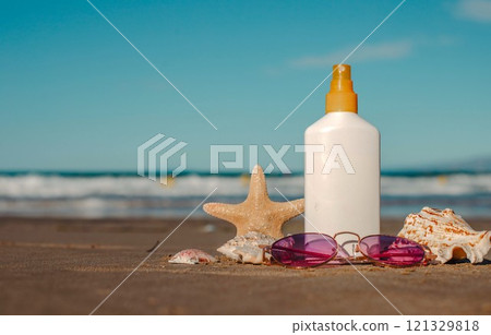 Beach essentials with sunscreen, sunglasses, starfish, and shells on sandy shore Beach essentials with sunscreen, sunglasses, starfish, and shells on sandy shore 121329818