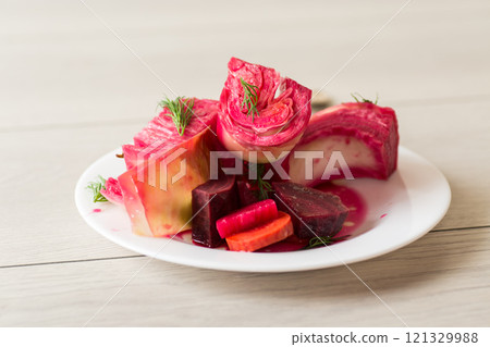 pickled cabbage with beets and carrots, in a plate, on a wooden table 121329988