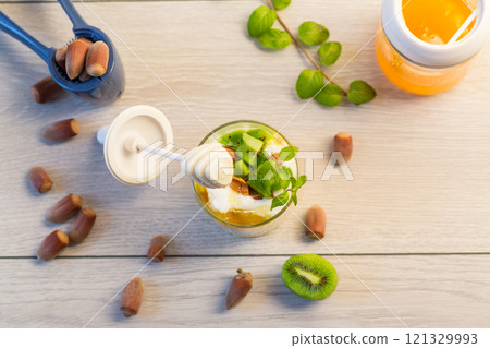 homemade yogurt with kiwi, honey and nuts in a glass on a wooden table homemade yogurt with kiwi, honey and nuts in a glass on a wooden table 121329993
