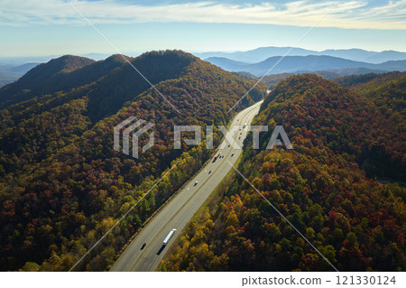 I-40 freeway road leading to Asheville in North Carolina thru Appalachian mountains with yellow fall forest and fast moving trucks and cars. Concept of high speed interstate transportation I-40 freeway road leading to Asheville in North Carolina thru Appalachian mountains with yellow fall forest and fast moving trucks and cars. Concept of high speed interstate transportation 121330124