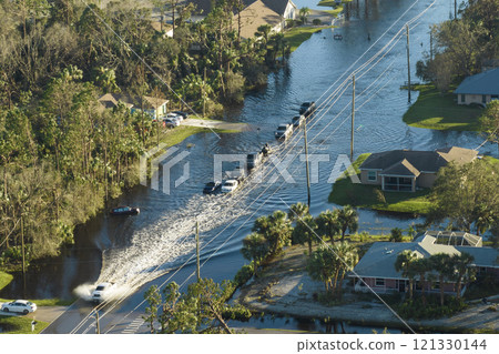 Hurricane flooded street with moving cars and surrounded with water houses in Florida residential area. Consequences of natural disaster 121330144