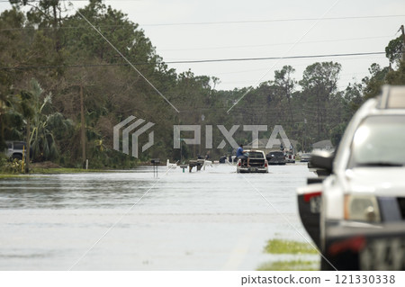 Flooded american street with moving vehicles surrounded with water in Florida residential area. Consequences of hurricane natural disaster Flooded american street with moving vehicles surrounded with water in Florida residential area. Consequences of hurricane natural disaster 121330338