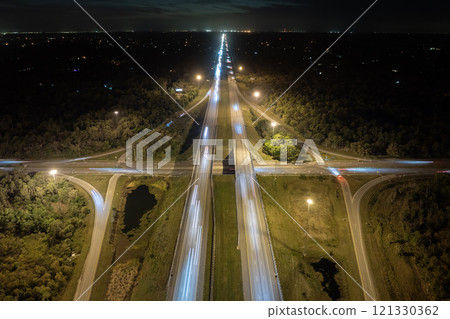 Elevated view of freeway exit junction over road lanes with fast moving traffic cars and trucks at sunrise. Interstate transportation infrastructure in USA Elevated view of freeway exit junction over road lanes with fast moving traffic cars and trucks at sunrise. Interstate transportation infrastructure in USA 121330362