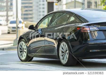 Electric car on Miami street. Traffic with driving cars at urban intersection with traffic lights in Florida Electric car on Miami street. Traffic with driving cars at urban intersection with traffic lights in Florida 121330363