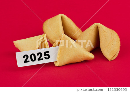 Fortune cookies with 2025 written on prophecy slips of paper, arranged on vibrant red background, symbolizing the future and prosperity 121330693
