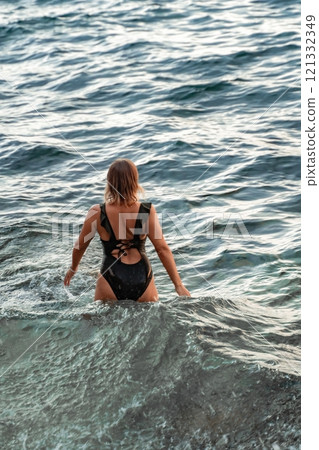 Woman Swimsuit Ocean Water - Woman in a black swimsuit wading in the ocean water. Woman Swimsuit Ocean Water - Woman in a black swimsuit wading in the ocean water. 121332349