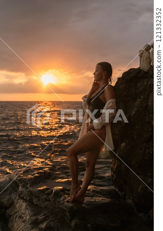 Woman Sunset Beach Rocky Coastline - Enjoying a scenic sunset by the ocean, a woman stands on a rocky coastline. Woman Sunset Beach Rocky Coastline - Enjoying a scenic sunset by the ocean, a woman stands on a rocky coastline. 121332352