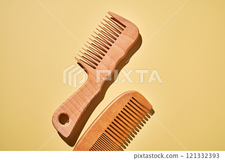 Two wooden combs on a yellow background. 121332393