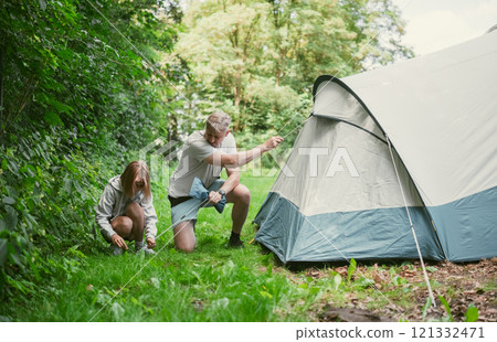 Father And Daughter Set Up A Tent At A Campground During Family Summer Camping Vacation Father And Daughter Set Up A Tent At A Campground During Family Summer Camping Vacation 121332471