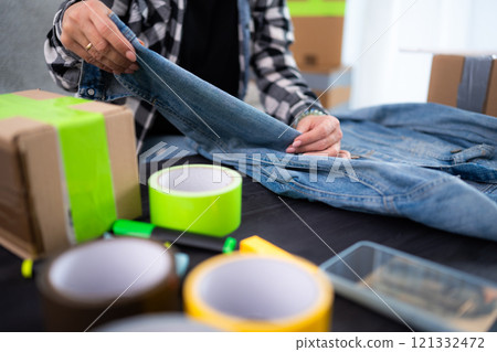 Young Woman Folds Jeans Jacket, Reflecting The Concept Of Clothing Order 121332472
