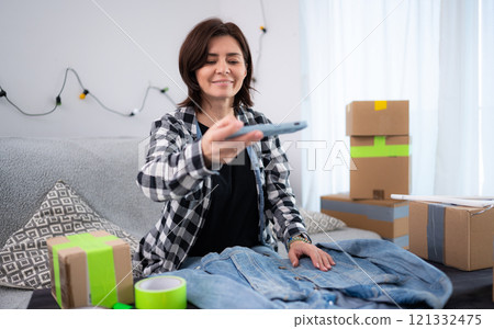 Young Woman At Home Taking Photos Of A Pre-Owned Jeans Jacket For Online Selling 121332475