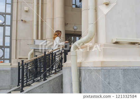 Woman Building Stairs Entrance - Woman walking down stairs outside building entrance. Woman Building Stairs Entrance - Woman walking down stairs outside building entrance. 121332584