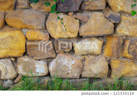 The masonry of the wall is made of natural layered stones, between which there are joints of different sizes made of mortar. Background of building materials 121333119