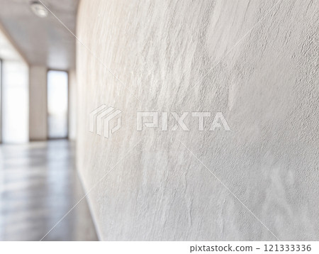 A minimalist hallway features a continuous microcement floor and wall, creating a seamless and spacious feel. 121333336