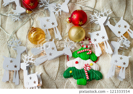 Christmas decorations, a toy Christmas tree on a beige knitted background 121333554
