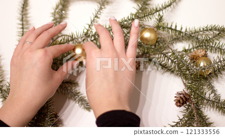 female hands decorate a New Year's wreath, preparing for the holiday 121333556