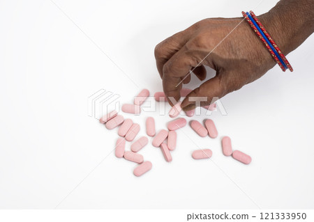 Female hand taking a pink pill on a white background, top view Female hand taking a pink pill on a white background, top view 121333950