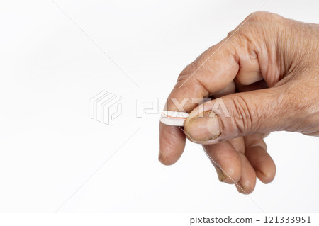 Close-up of a hand holding a damaged pill on a white background 121333951