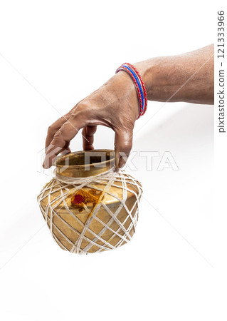 Hand holding a brass jar decorated with ethnic significance, Closeup 121333966