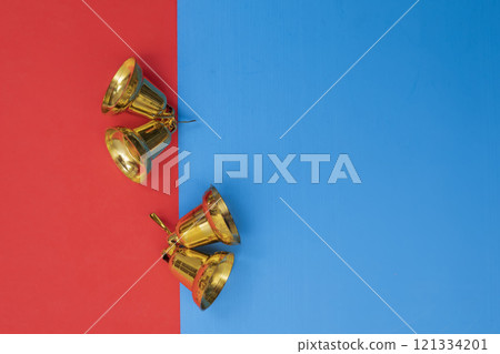 Top view of golden bells on a bright red and blue background, symbolizing celebration 121334201
