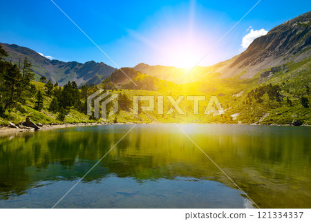 Bright sunrise over a picturesque small lake high in mountains against sky. 121334337