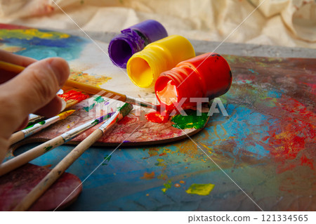 art acrylic paints yellow red and purple lie open on palette next to brushes 121334565