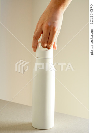 Male hand holding stainless steel bottle with handle, close-up Male hand holding stainless steel bottle with handle, close-up 121334570
