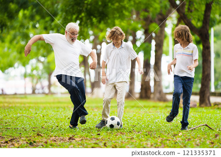 Grandfather and kids play football in summer park 121335371