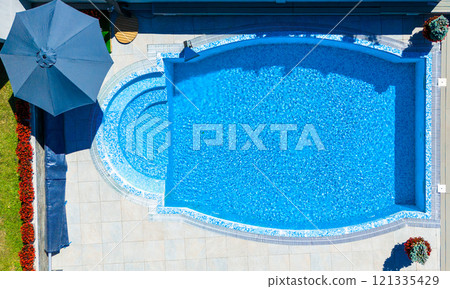 Top view of a luxurious oval pool with mosaic tiles and surrounding patio 121335429