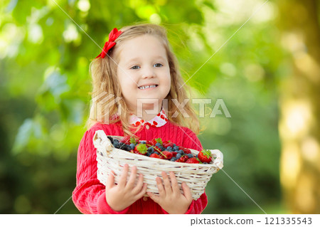 Little girl with fresh berries in a basket 121335543