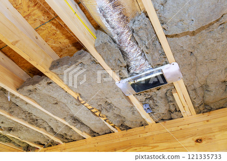New insulation material is installed in building, showcasing ventilation duct, wooden beams overhead. 121335733