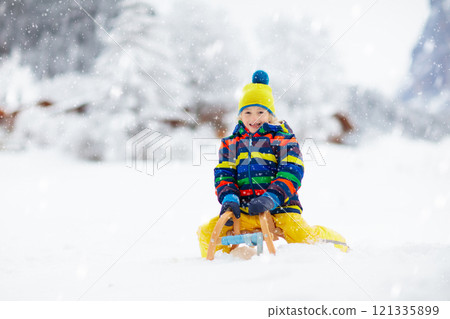 Boy on sled ride. Child sledding. Kid on sledge 121335899
