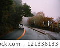 White car driving on a foggy mountain road 121336133
