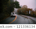 White car driving on a foggy mountain road 121336134