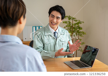 A man in work clothes doing sales by showing a computer A man in work clothes doing sales by showing a computer 121336250