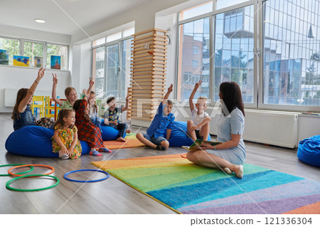 Reading time in an elementary school or kindergarten, a teacher reads a book to children in an elementary school or kindergarten. The concept of pre-school education. Selective focus 121336304