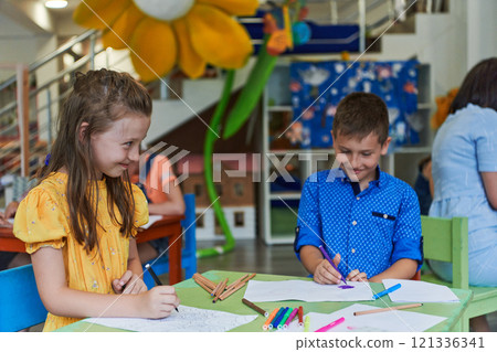 Cute girl and boy sit and draw together in preschool institution Cute girl and boy sit and draw together in preschool institution 121336341