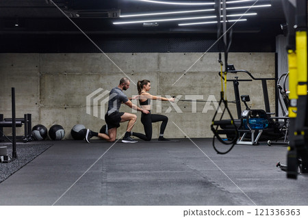 A muscular man assisting a fit woman in a modern gym as they engage in various body exercises and muscle stretches, showcasing their dedication to fitness and benefiting from teamwork and support A muscular man assisting a fit woman in a modern gym as they engage in various body exercises and muscle stretches, showcasing their dedication to fitness and benefiting from teamwork and support 121336363