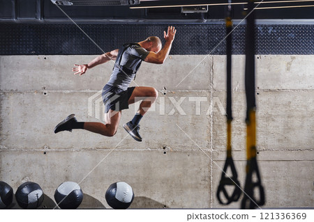 A muscular man captured in air as he jumps in a modern gym, showcasing his athleticism, power, and determination through a highintensity fitness routine 121336369