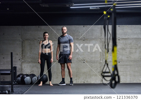 Muscular man and fit woman in a conversation before commencing their training session in a modern gym. Muscular man and fit woman in a conversation before commencing their training session in a modern gym. 121336370