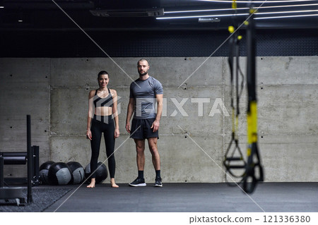 Muscular man and fit woman in a conversation before commencing their training session in a modern gym. 121336380