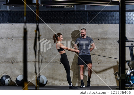 A muscular man assisting a fit woman in a modern gym as they engage in various body exercises and muscle stretches, showcasing their dedication to fitness and benefiting from teamwork and support A muscular man assisting a fit woman in a modern gym as they engage in various body exercises and muscle stretches, showcasing their dedication to fitness and benefiting from teamwork and support 121336406