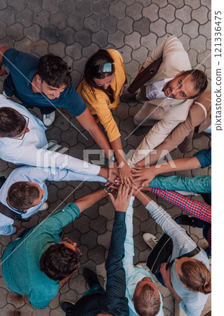 Top view photo of a group of business people and colleagues standing together holding hands, looking towards the camera, symbolizing unity and teamwork. Top view photo of a group of business people and colleagues standing together holding hands, looking towards the camera, symbolizing unity and teamwork. 121336475