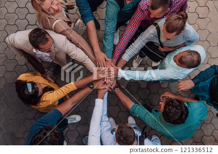 Top view photo of a group of business people and colleagues standing together holding hands, looking towards the camera, symbolizing unity and teamwork. 121336512
