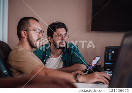 Programmers engrossed in deep collaboration, diligently working together to solve complex problems and develop innovative mobile applications with seamless functionality. 121336635