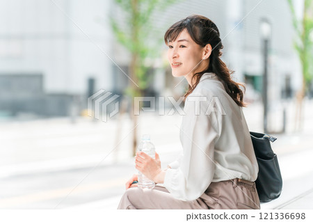 A businesswoman drinking bottled water/drinks while out A businesswoman drinking bottled water/drinks while out 121336698