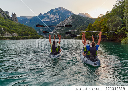 A group of friends enjoying fun and kayaking exploring the calm river, surrounding forest and large natural river canyons during an idyllic sunset. 121336819