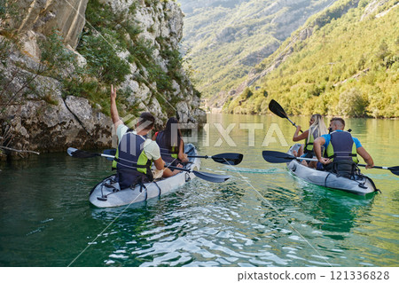 A group of friends enjoying having fun and kayaking while exploring the calm river, surrounding forest and large natural river canyons A group of friends enjoying having fun and kayaking while exploring the calm river, surrounding forest and large natural river canyons 121336828