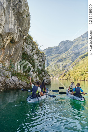 A group of friends enjoying having fun and kayaking while exploring the calm river, surrounding forest and large natural river canyons 121336990
