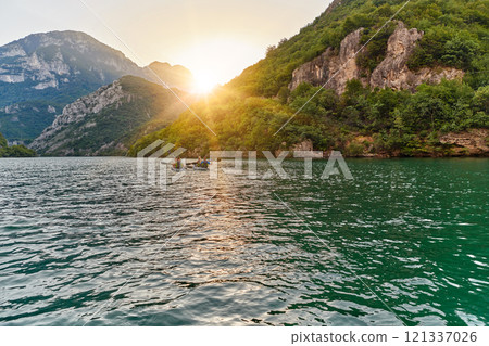 A group of friends enjoying fun and kayaking exploring the calm river, surrounding forest and large natural river canyons during an idyllic sunset. 121337026